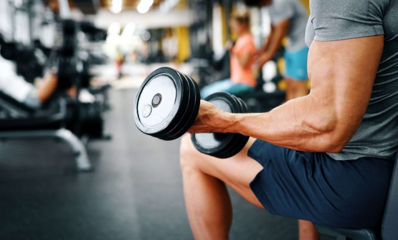 fit guy doing bicept curls in gym